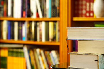 library with lots of books to read, computer on shelves. Stacked books in the foreground. Copy space.