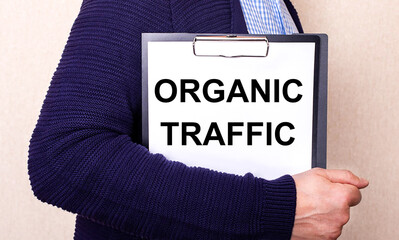 ORGANIC TRAFFIC is written on a white sheet held by a man standing sideways