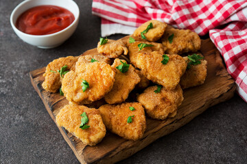 Homemade chicken nuggets with herbs and ketchup on a wooden board