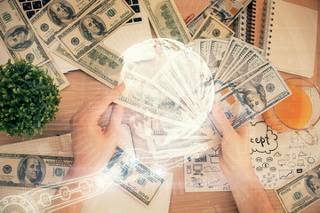Double exposure of world map drawing hologram and us dollars bills and man hands.