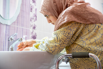 Muslim woman with disability is washing her hands