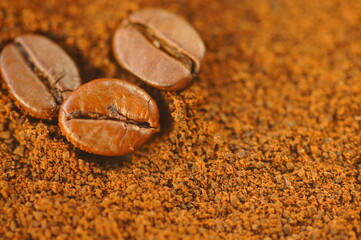 Three coffee beans on a brown background. Coffee beans on ground coffee. Macro magnification of...