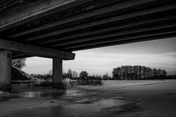 winter landscape under the bridge, highway over ice and snow covered river.