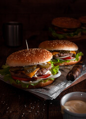 Burgers on the paper and a wooden Board on a dark background