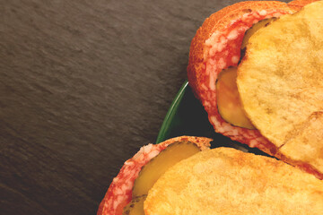 Sandwiches with bread slices cheese salt cucumber and crisps on green saucer. Filling background.