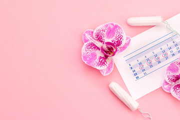 Obraz na płótnie Canvas Empty space for text. Menstruation. Calendar, tampons, orchid flowers on a pink background.