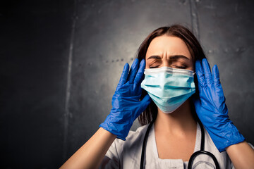 Nurse worker have headache migraine close eyes feel bad pain tired owerworked. Female doctor dressed medical white gown with stethoscope blue disposable face mask and gloves