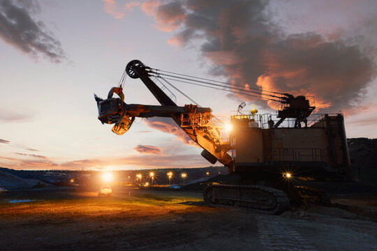 Silhouette of a mechanical digger at an iron ore mine at sunset, Thailand