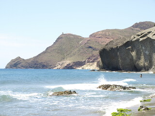 Fototapeta na wymiar Formaciones rocosas de origen volcánico y acantilados junto a una playa de la costa del mediterráneo andaluz