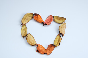 A heart made with yellow-orange rose petals white background