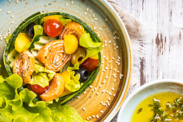 Salmon salad with green leaves, avocado and tomato. Prepared by chef.