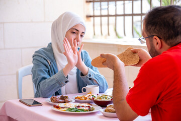 Couples are eating breakfast together and the girl is refusing to take the bread