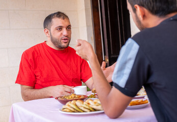Muslim man and his friend are eating together and talking about many things
