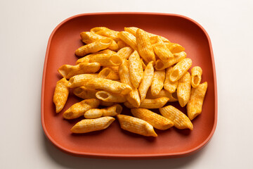 Crispy penne pasta shaped salty. Fast food or junk food snacks unhealthy concept.