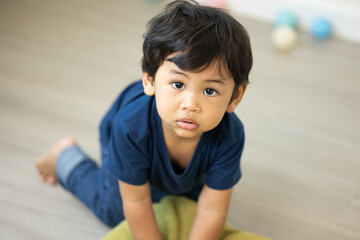 An Asian boy about 1 year old. Play in the living room of the house. He is wearing a blue shirt.