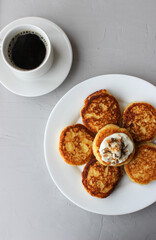 Breakfast of cheesecakes on a plate with sour cream.