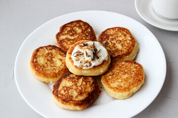 Breakfast of cheesecakes on a plate with sour cream.