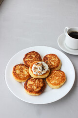 Breakfast of cheesecakes on a plate with sour cream.