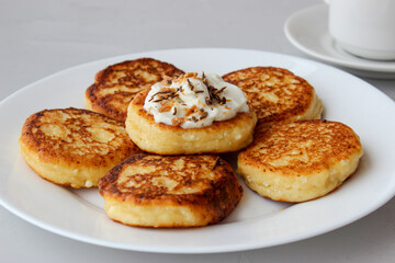 Breakfast of cheesecakes on a plate with sour cream.
