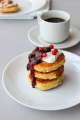 Breakfast of cheesecakes on a plate with sour cream.