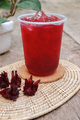 Red Roselle Juice, Thai herbal juice, sweet and sour taste in a glass, placed on a wooden table.