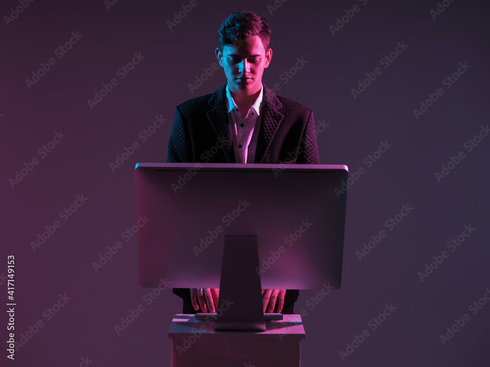 Poster man works at a computer while standing. a monitor stand next to man. businessman and computer on a d