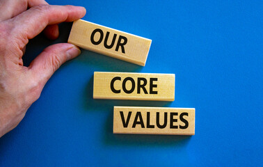 Our core values symbol. Concept words 'Our core values' on wooden blocks on a beautiful blue background, businessman hand. Business and our core values concept. Copy space.