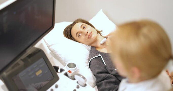 Doctor examining thyroid of female patient with ultrasound scan in medical spa. Concept of ultrasound examination and health checkup