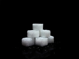 Lump sugar cubes on black background, isolated cubes of white sugar on black background