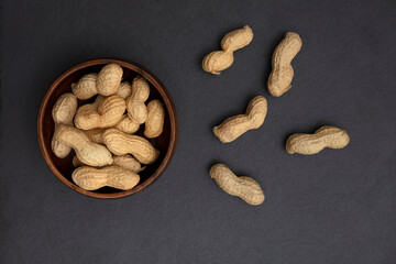 Shelled peanuts in bowl on black background