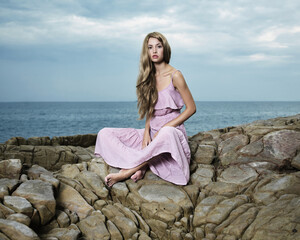 Beautiful blonde woman on the beach. Lady in pink dress