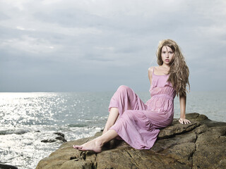 Beautiful blonde woman on the beach. Lady in pink dress