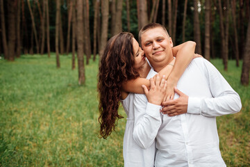 Obraz premium A couple in love beautiful young man and woman are hugging in a summer park on a sunny day. Date outside, well dressed, so excited and lovely