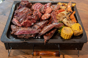 Complete grill of Argentine Asado of meat with vegetables and served in Brasero