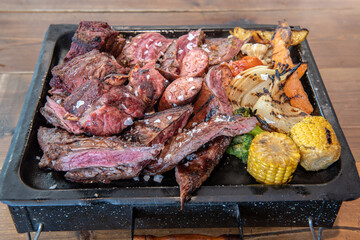 Complete grill of Argentine Asado of meat with vegetables and served in Brasero