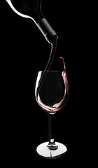 Close-up view of Red wine is poured from bottle into a glass on black background