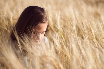 little girl with dark hairs portrait - in sunny summer field with rye 