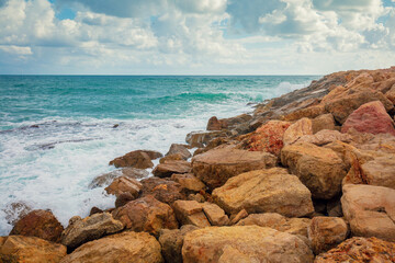 Fototapeta na wymiar Rocky beach with big brown stones and cloudy sky
