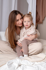 Smiling young mother embracing little girl. Attractive young mommy holding on lap little adorable daughter. Two people close up