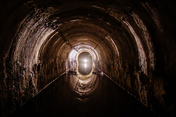 Naklejka premium Flooded round sewer tunnel with water reflection