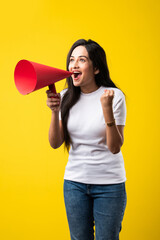 Indian pretty young woman screaming, announcing using red paper megaphone against yellow background