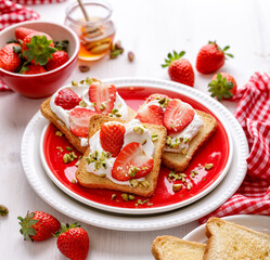 Delicious homemade toasts with fresh strawberries and cream cheese sprinkled with pine nuts,...