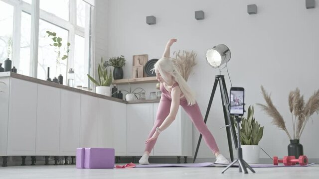 online sport coach concept. young white woman fitness coach in sportswear at home conducts individual workout in online class. Home workout training. Health practice and wellness concept
