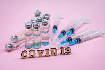 Medical ampoules and syringes on a pink background. Vaccination against covid-19.