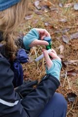 Woman playing geocaching game opening a cache during hiking. 