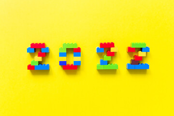 Obraz premium multicolored numbers 2022 from kids constructor set on isolated yellow background with place for text