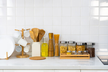 picture of kitchenware, cooking tools, utensils, dish, mug, raw pasta, olive oil, garnish and pepper in white kitchen with copy space