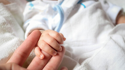 Newborn baby holding father's hand
