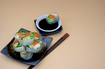 Close up of Japanese sushi rolls stacked on a plate with soy sauce for dipping and chopsticks