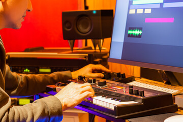 male music producer enjoy arranging a song on midi keyboard and computer in home studio